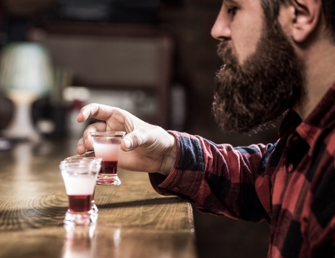 Man at a bar drinking shots of alcohol wondering can you get drunk off one shot